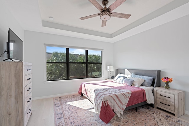 bedroom featuring a tray ceiling, ceiling fan, and light hardwood / wood-style floors