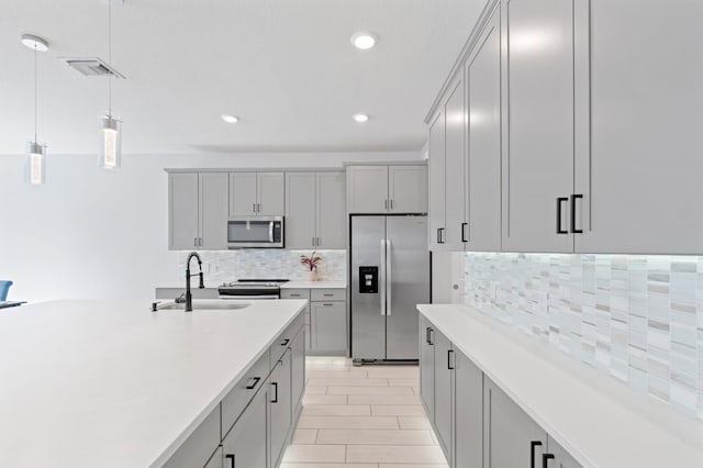 kitchen with stainless steel appliances, gray cabinets, hanging light fixtures, and sink