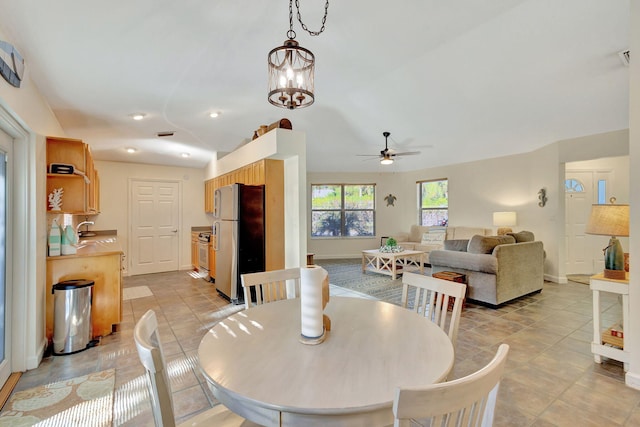 tiled dining space featuring sink and ceiling fan with notable chandelier