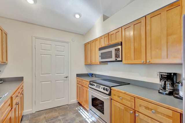 kitchen with appliances with stainless steel finishes, vaulted ceiling, and light brown cabinetry