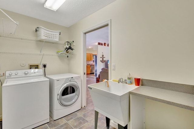 laundry room with washer and clothes dryer, sink, and a textured ceiling