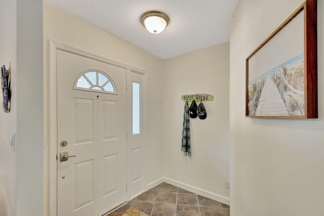 foyer entrance with a textured ceiling and tile patterned floors