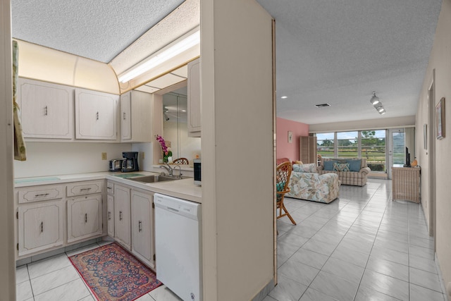 kitchen with dishwasher, light tile patterned floors, a textured ceiling, and sink