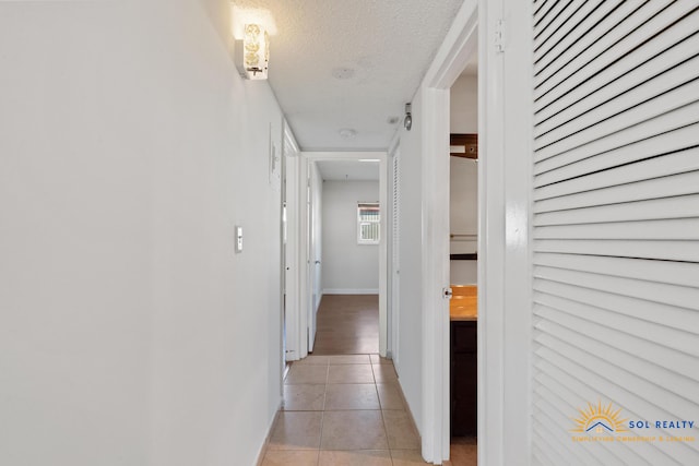 hallway with light tile patterned floors and a textured ceiling