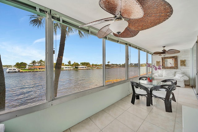 sunroom featuring a water view, ceiling fan, and a healthy amount of sunlight