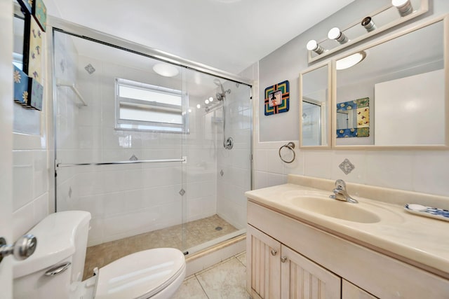 bathroom with vanity, a shower with door, toilet, and tile walls