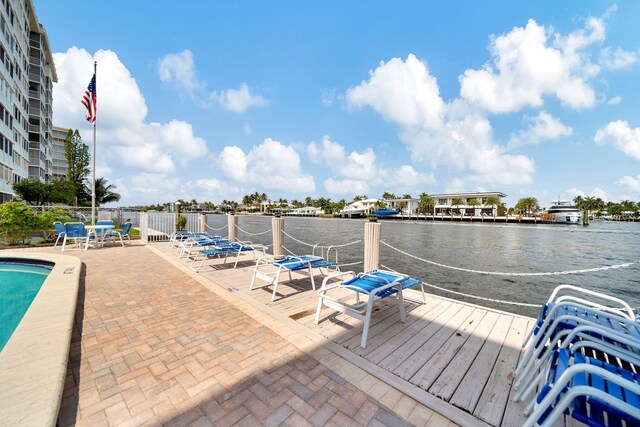 dock area featuring a community pool, a water view, and a patio