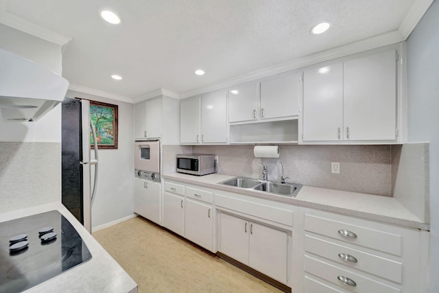 kitchen with sink, light hardwood / wood-style flooring, white cabinets, black appliances, and ornamental molding