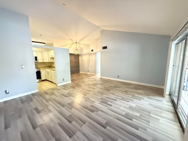 unfurnished living room featuring a chandelier, light hardwood / wood-style floors, and vaulted ceiling