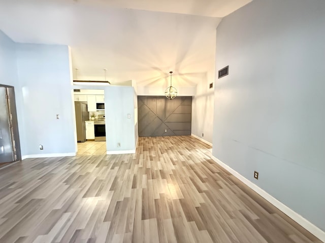 unfurnished living room featuring light wood-type flooring and an inviting chandelier