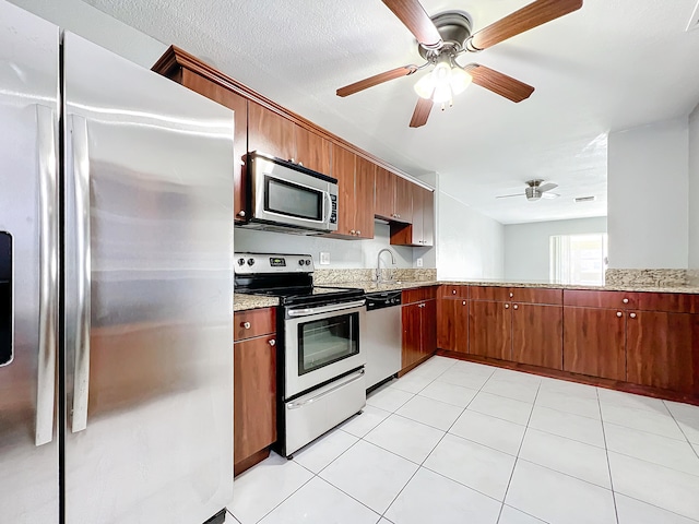 kitchen with appliances with stainless steel finishes, light tile patterned floors, ceiling fan, and sink