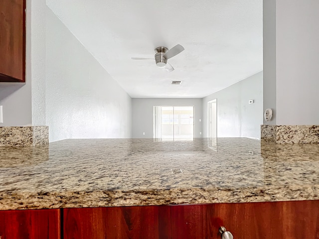 kitchen with ceiling fan and light stone countertops