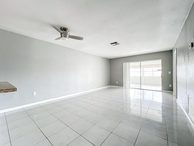 tiled empty room with ceiling fan and a textured ceiling