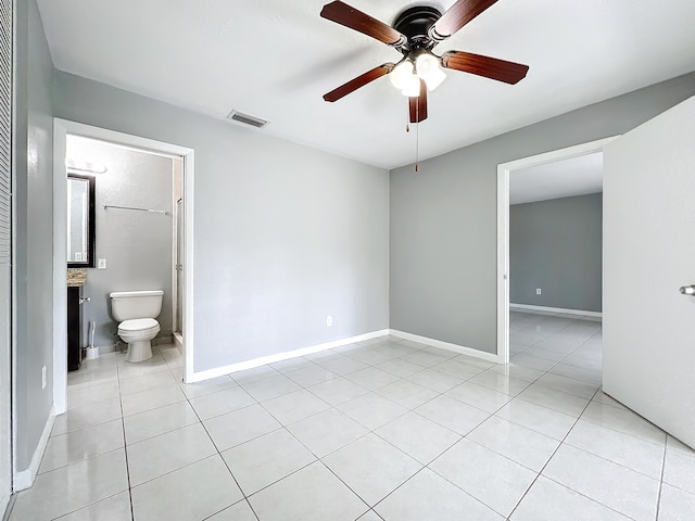 unfurnished bedroom featuring ceiling fan, light tile patterned floors, and ensuite bathroom