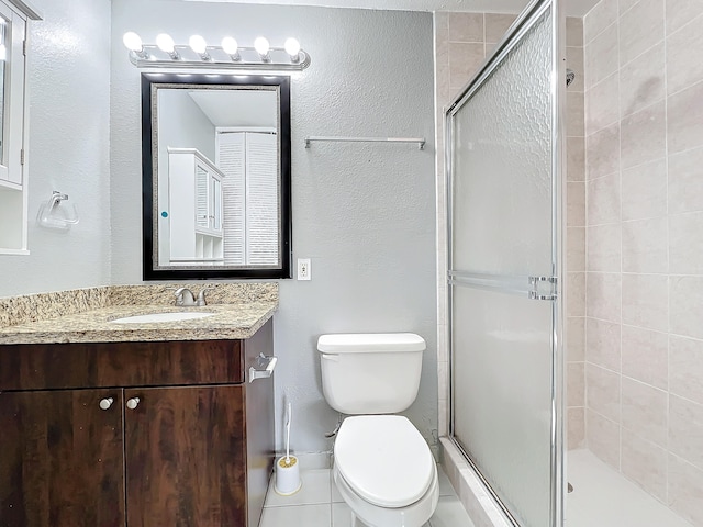 bathroom with tile patterned flooring, vanity, toilet, and walk in shower