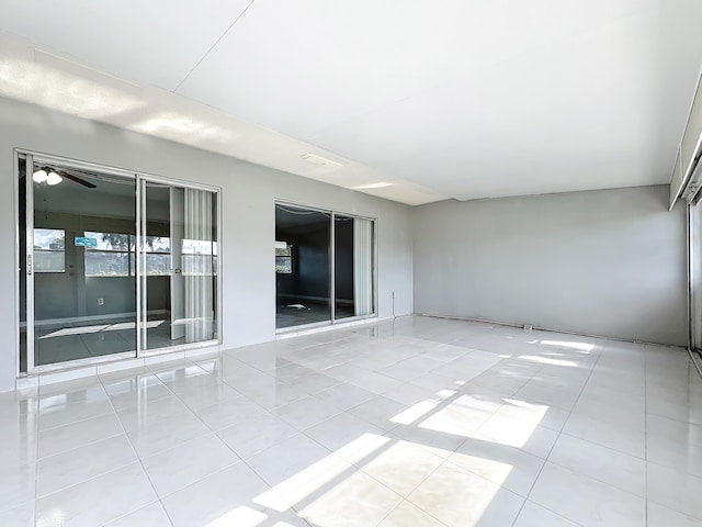 tiled empty room featuring ceiling fan