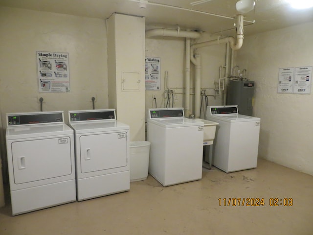 clothes washing area featuring electric water heater, separate washer and dryer, and sink