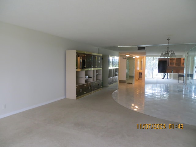 unfurnished living room with carpet flooring and an inviting chandelier