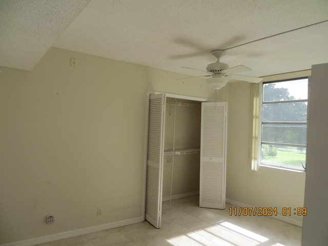 unfurnished bedroom featuring a textured ceiling, a closet, multiple windows, and ceiling fan