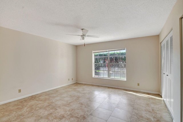 tiled spare room with a textured ceiling and ceiling fan