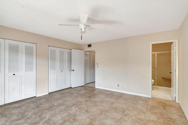 unfurnished bedroom featuring connected bathroom, two closets, a textured ceiling, and ceiling fan