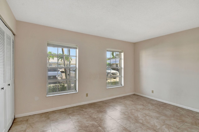 empty room with light tile patterned flooring and a textured ceiling