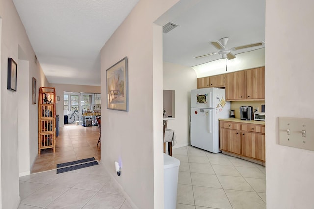 kitchen featuring white fridge, ceiling fan, and light tile patterned flooring