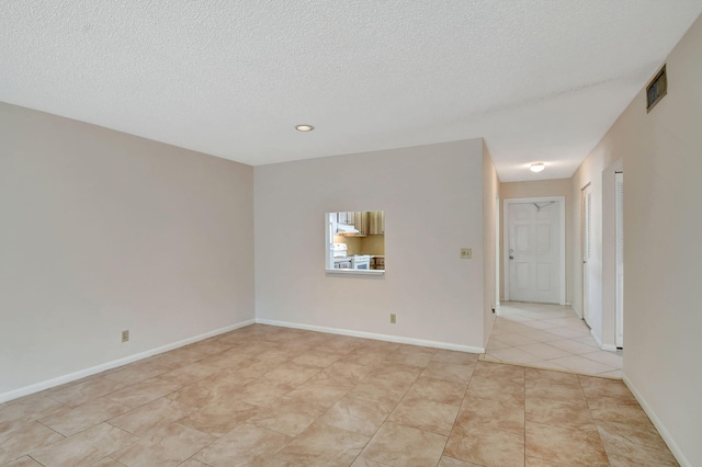 tiled empty room featuring a textured ceiling