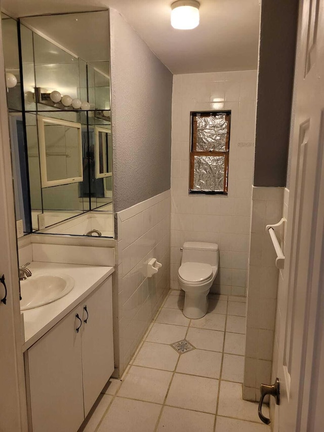 bathroom with tile patterned flooring, vanity, toilet, and tile walls