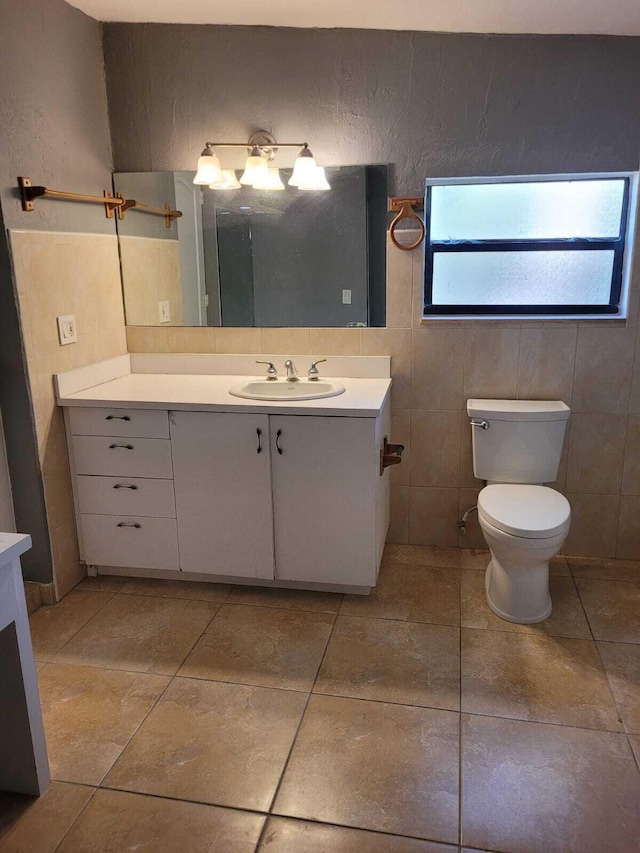 bathroom with tile patterned flooring, vanity, tile walls, and toilet