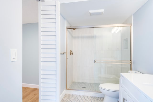 bathroom with hardwood / wood-style floors, vanity, toilet, and walk in shower