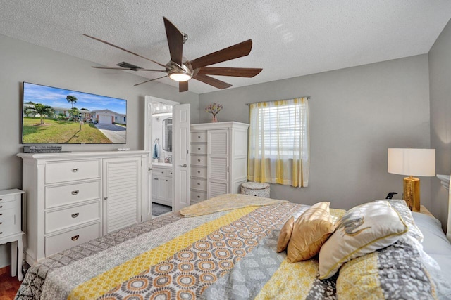 bedroom with ceiling fan, a textured ceiling, and connected bathroom