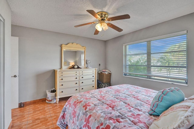 bedroom featuring light wood-type flooring, a textured ceiling, and ceiling fan