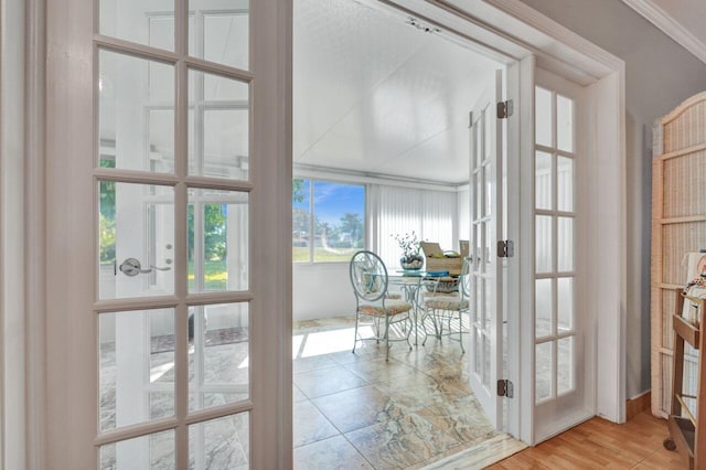 entryway with french doors, crown molding, and wood-type flooring