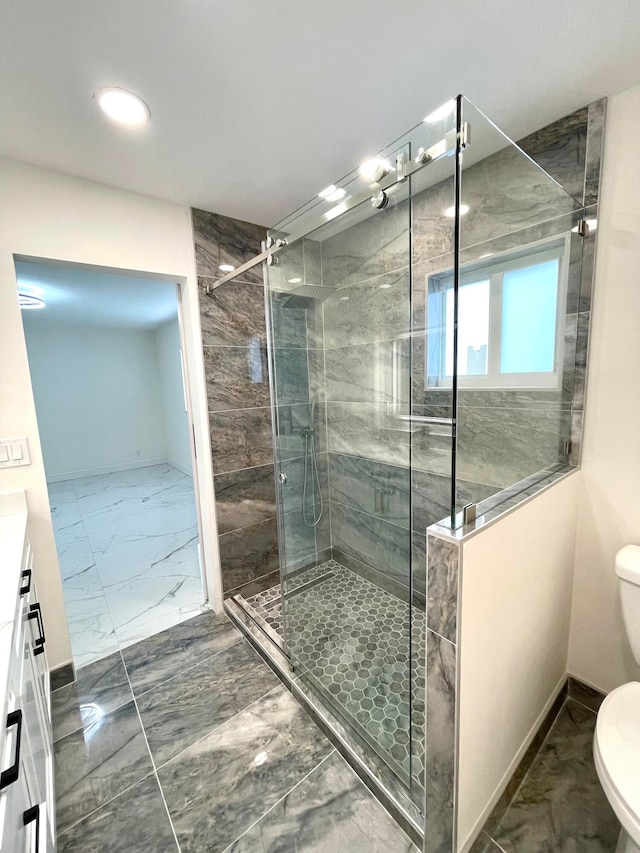 bathroom with a tile shower, vanity, and toilet