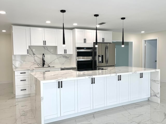 kitchen featuring white cabinets, decorative light fixtures, stainless steel appliances, and a spacious island