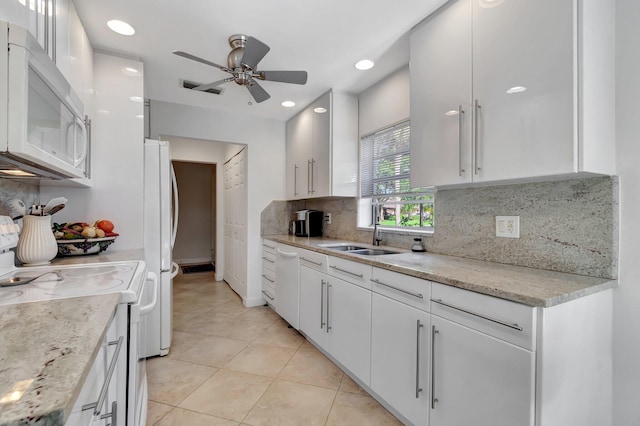 kitchen with decorative backsplash, light stone counters, white appliances, sink, and white cabinetry