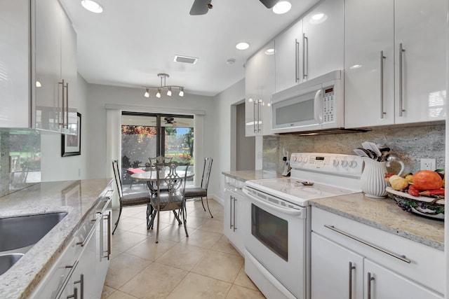 kitchen with backsplash, light tile patterned floors, white cabinets, and white appliances