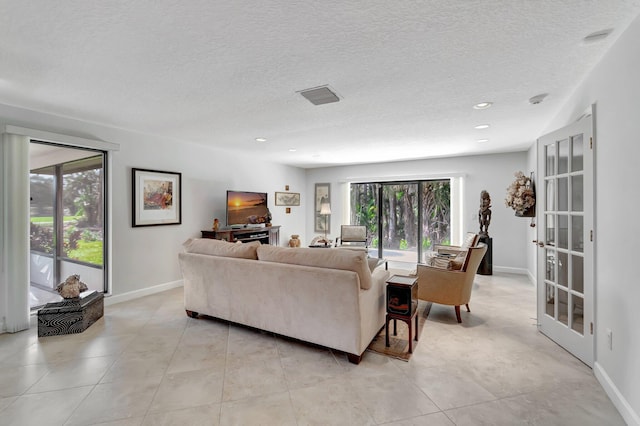 tiled living room with french doors, a textured ceiling, and plenty of natural light