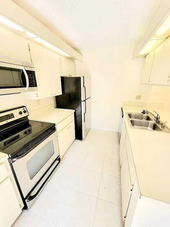 kitchen featuring white cabinets, black refrigerator, sink, a textured ceiling, and white range with electric stovetop