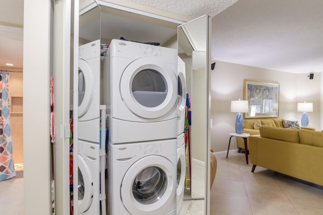 washroom with stacked washer / dryer, light tile patterned floors, and a textured ceiling