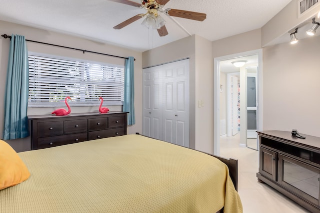 tiled bedroom with a textured ceiling, track lighting, a closet, and ceiling fan