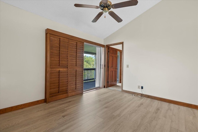 unfurnished room with lofted ceiling, light wood-style floors, baseboards, and a ceiling fan