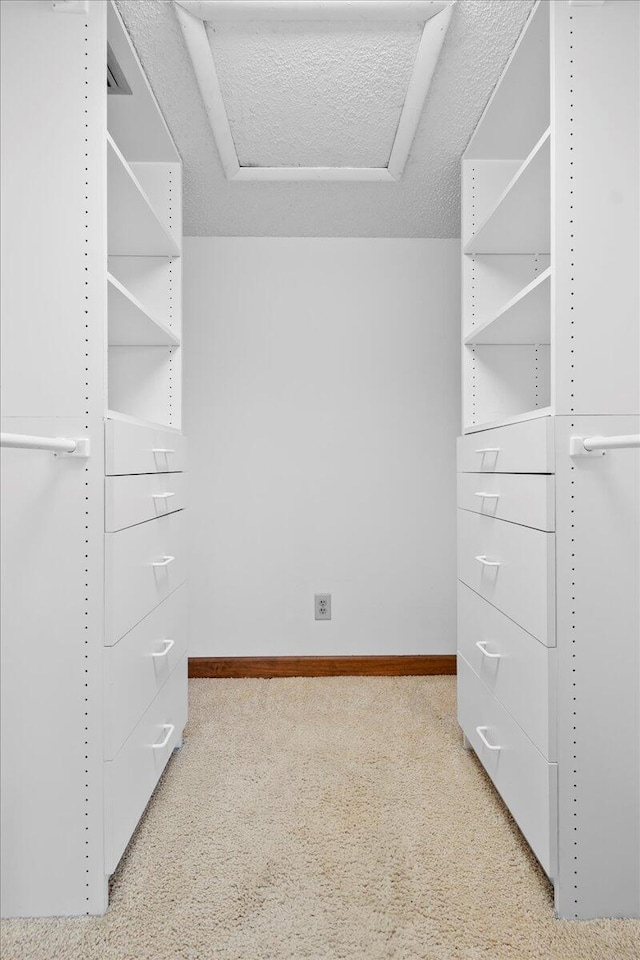 spacious closet with attic access and light colored carpet