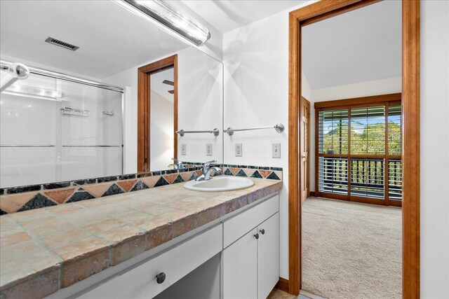 full bathroom featuring vaulted ceiling, a stall shower, vanity, and visible vents