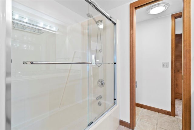 bathroom featuring shower / bath combination with glass door, tile patterned flooring, and baseboards