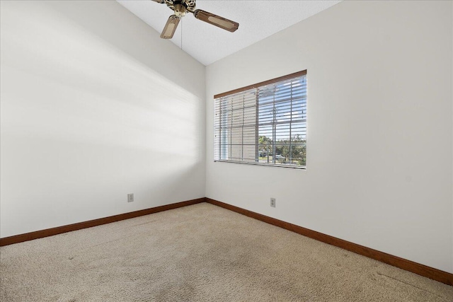 spare room with ceiling fan, vaulted ceiling, carpet, and baseboards