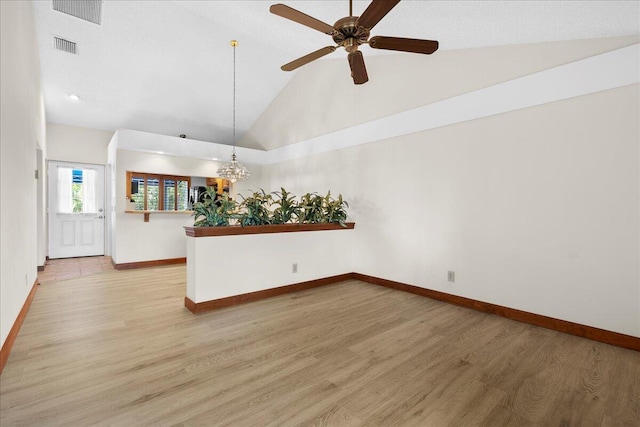 empty room with visible vents, light wood-style flooring, a ceiling fan, high vaulted ceiling, and baseboards