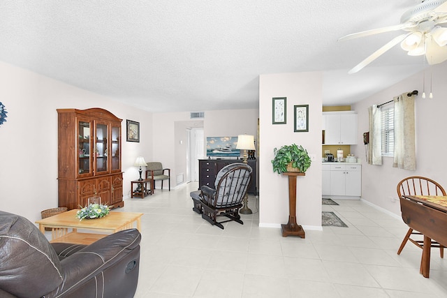 tiled living room with a textured ceiling and ceiling fan