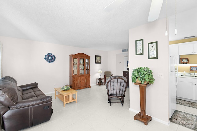 living room featuring a textured ceiling, ceiling fan, and sink